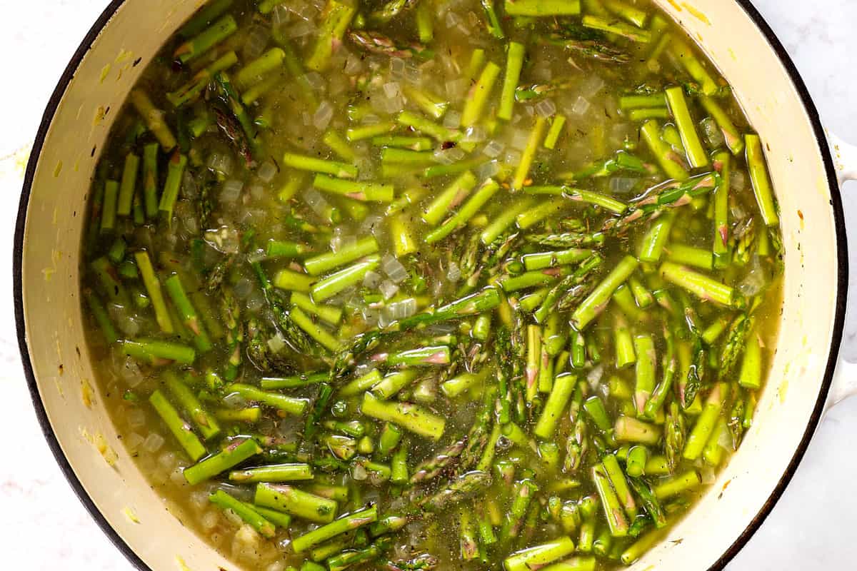 showing how to make Cream of Asparagus Soup by simmering asparagus until tender with broth, onions and garlic
