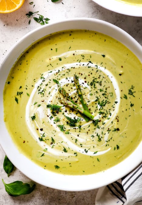 top view of Creamy Asparagus Soup in bowls garnished by asparagus spears and fresh dill