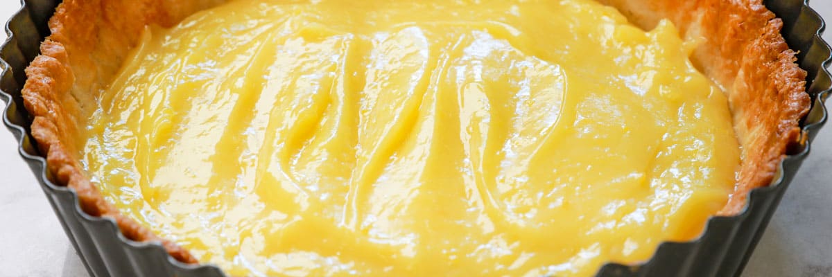 showing how to make Lemon Meringue Pie by transferring lemon filling to a partially baked pie crust