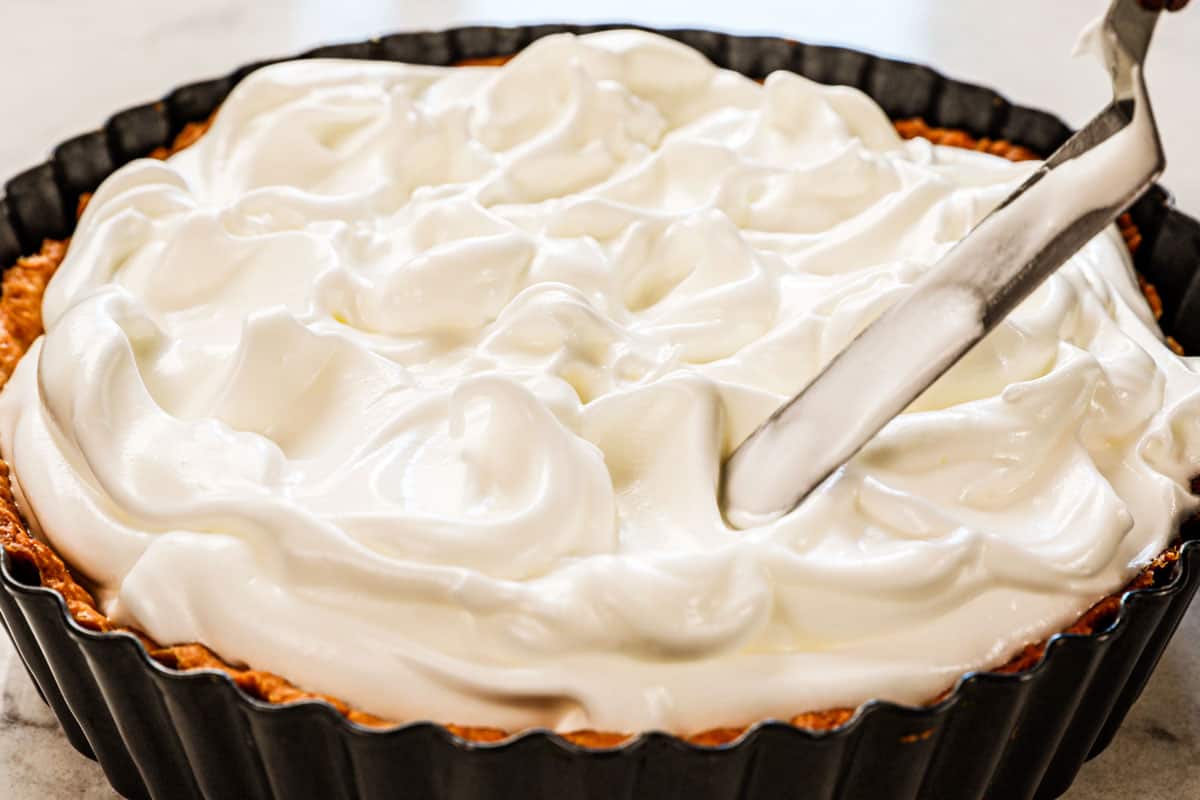 showing how to make best Lemon Meringue Pie recipe by spreading the meringue over the lemon filling, then swirling with the back of a spoon