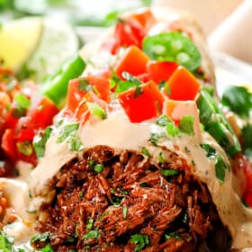 up close of chimichanga with shredded beef and sauce topped with pico de gallo