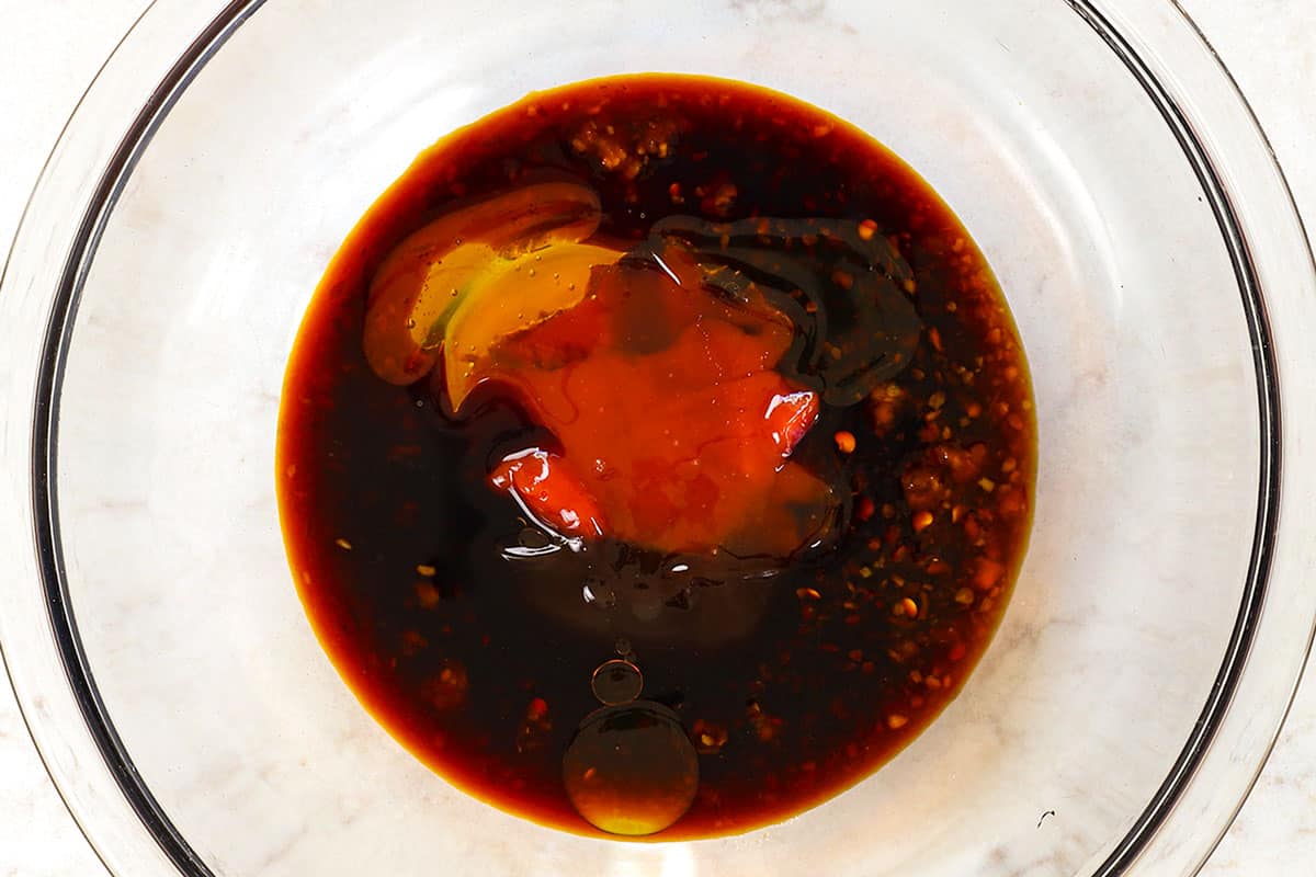 showing how to make spicy Dragon Chicken by whisking together chili sauce, soy sauce, oyster sauce, honey and ketchup to make the sauce