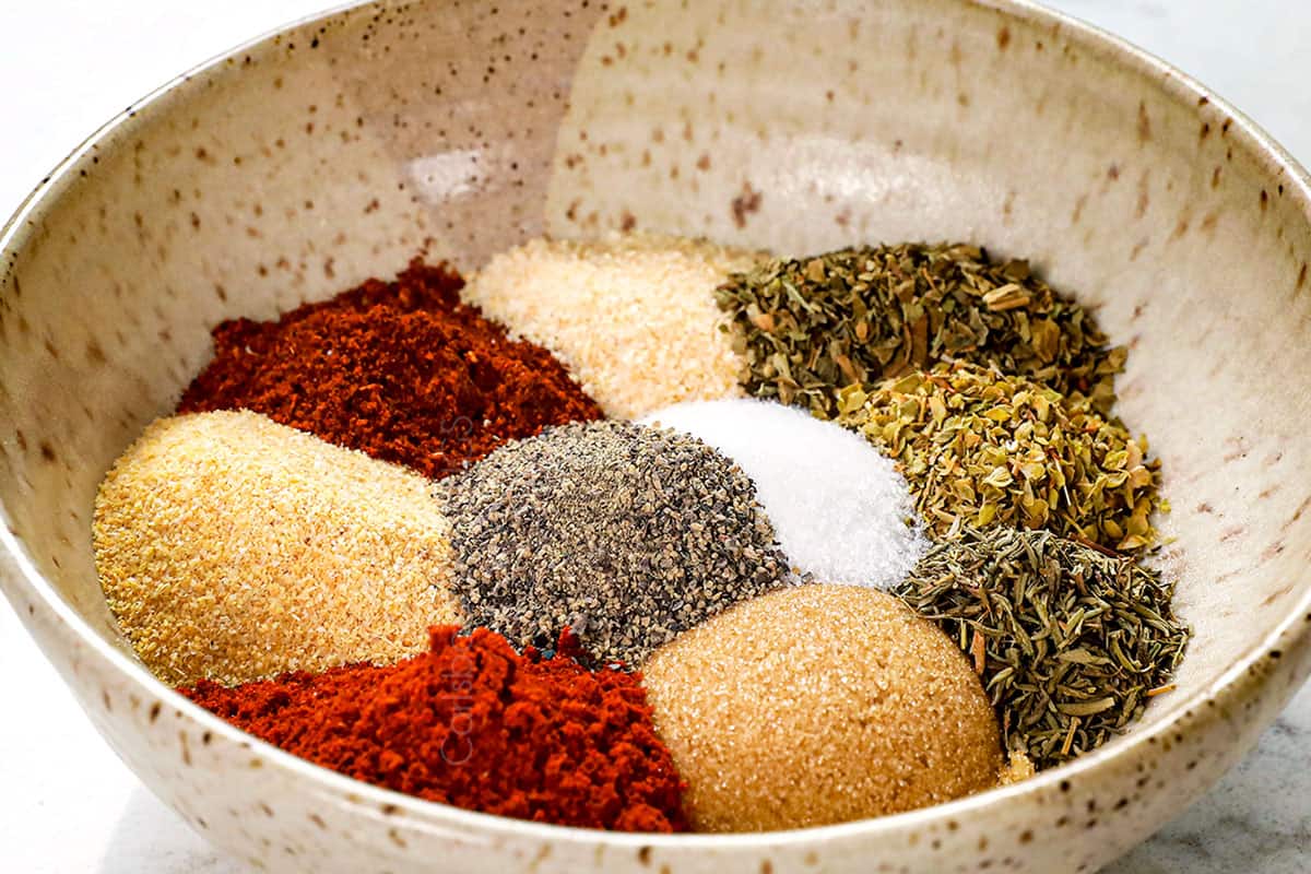 showing how to bake chicken thighs by whisking all of the seasonings together in a bowl to create a chicken rub
