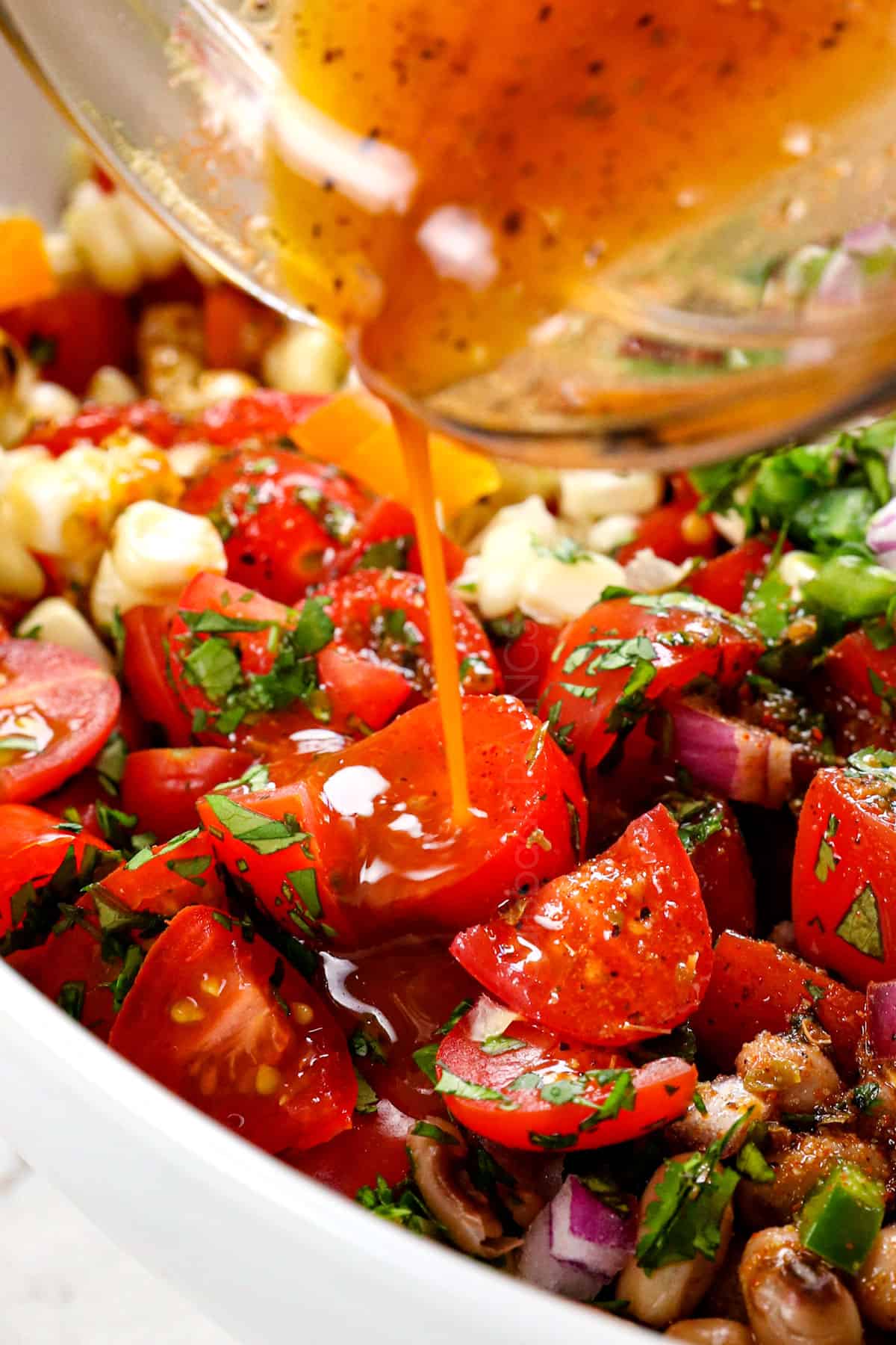 showing how to make cowboy caviar recipe (Texas Caviar recipe) by pouring the tangy dressing over the dip