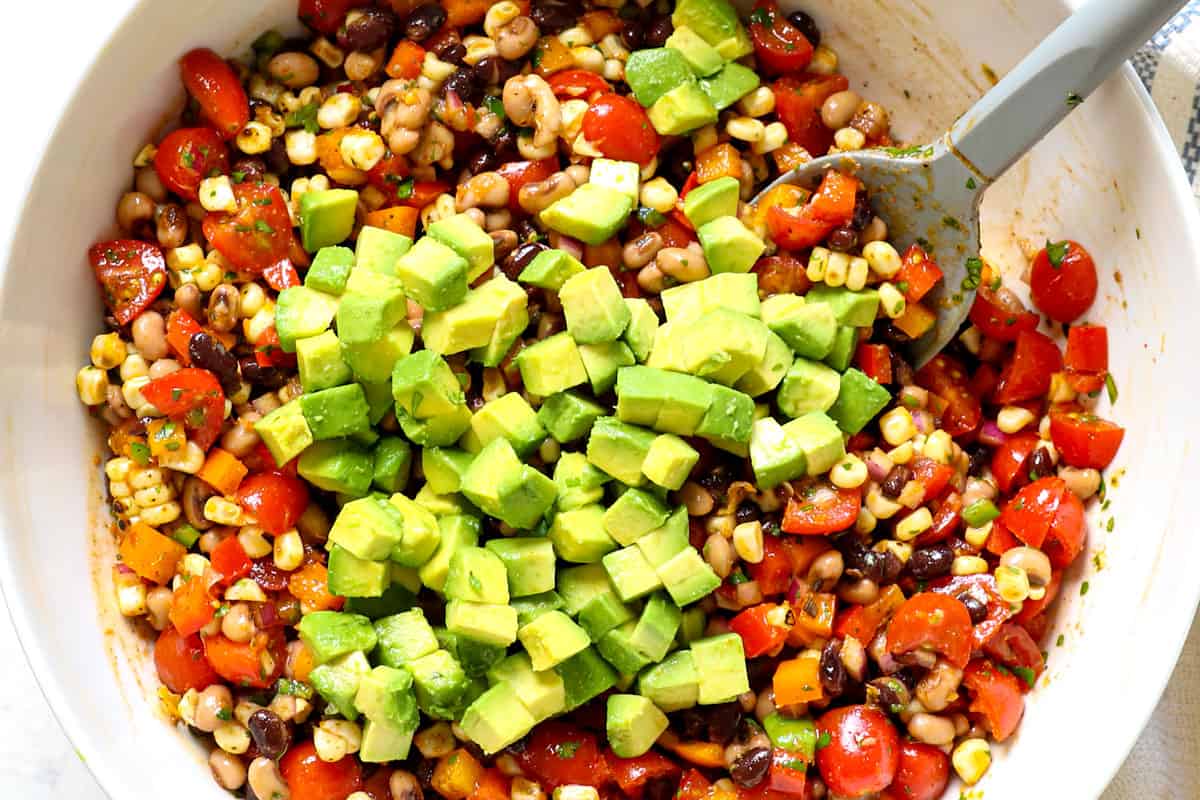 showing how to make Texas Caviar (Cowboy Caviar) by adding avocados to the recipe