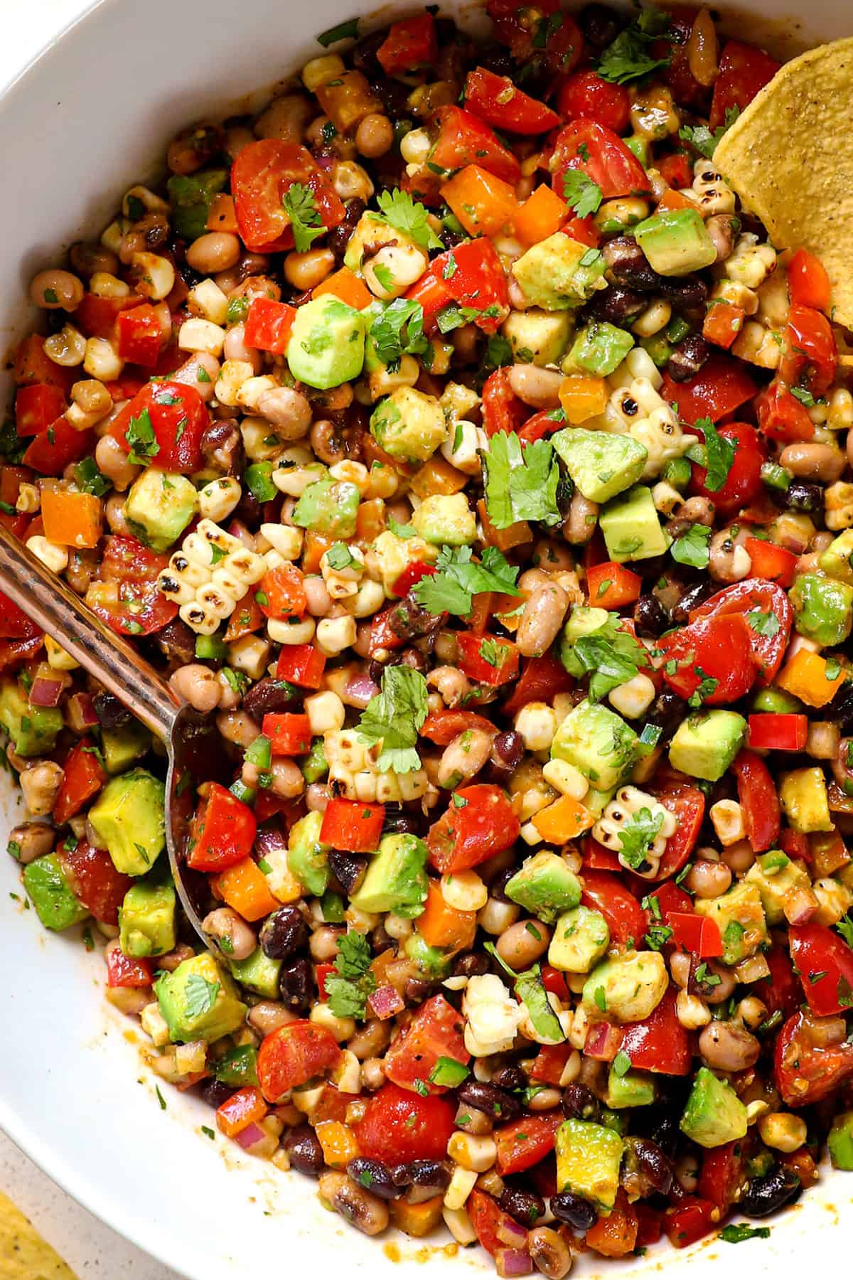 cowboy caviar dip (Texas Caviar) being served in a white bowl with tortilla chips