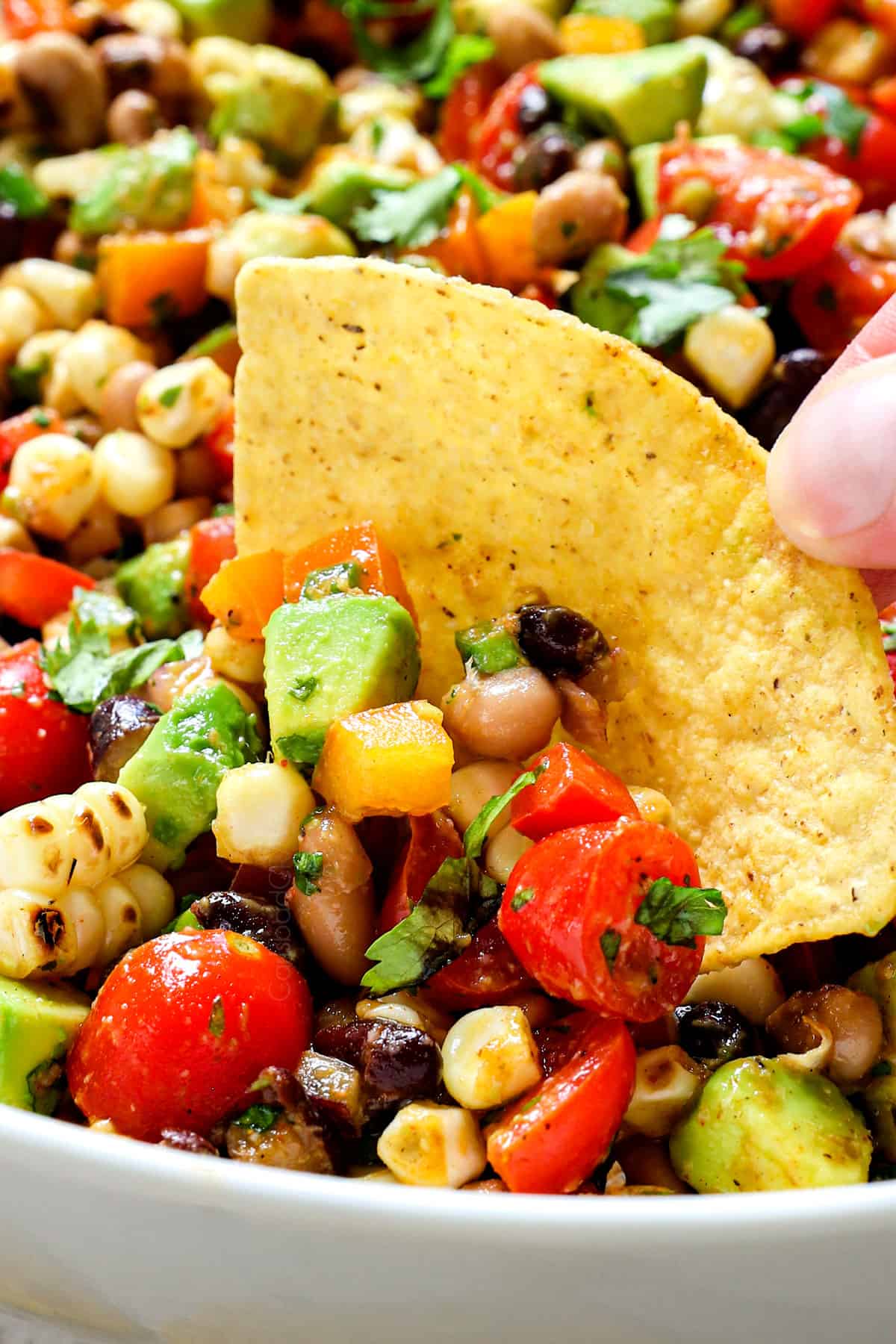 showing how to serve Cowboy Caviar Dip by scooping it up with tortilla chips