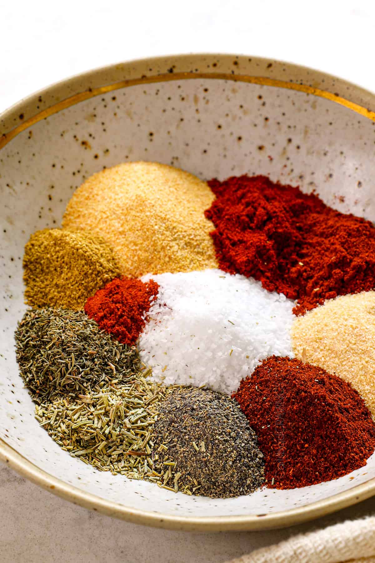 top view of steak seasoning ingredients in a bowl: kosher salt, garlic powder, onion powder, smoked paprika, chili powder, pepper, cayenne pepper, thyme, rosemary and ground coriander