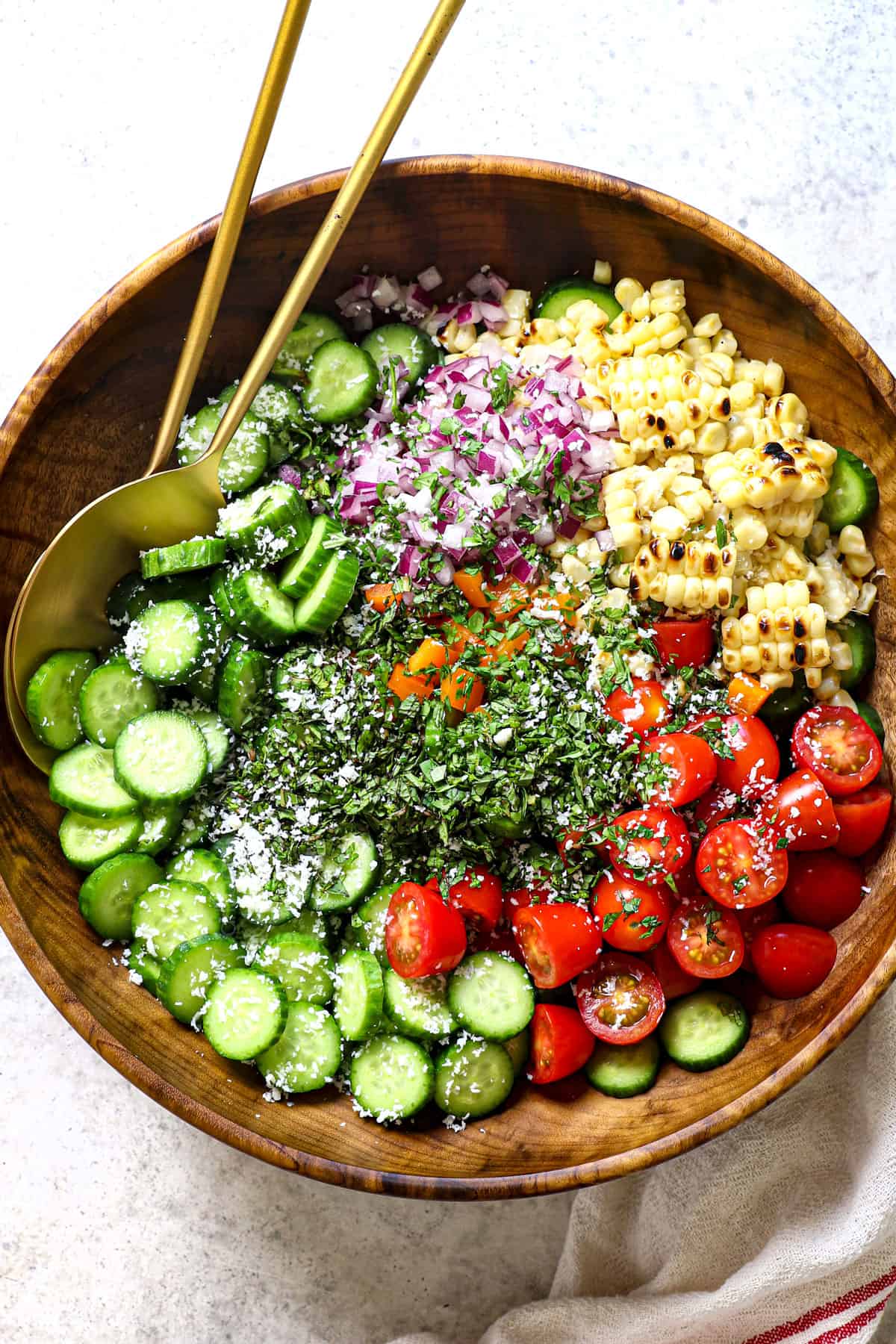 top view of cucumber salad ingredients in a bowl with cucumbers, tomatoes, corn, onions, bell peppers