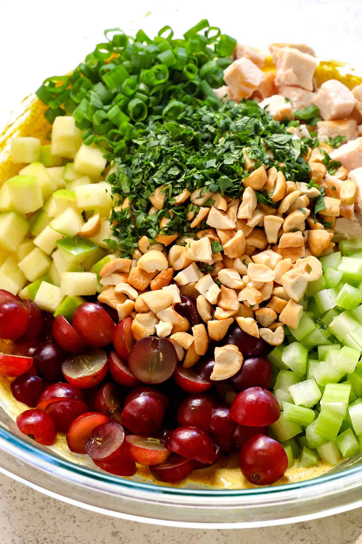 up close showing curried chicken salad ingredients: chicken, grapes, nuts, celery, onions and apples