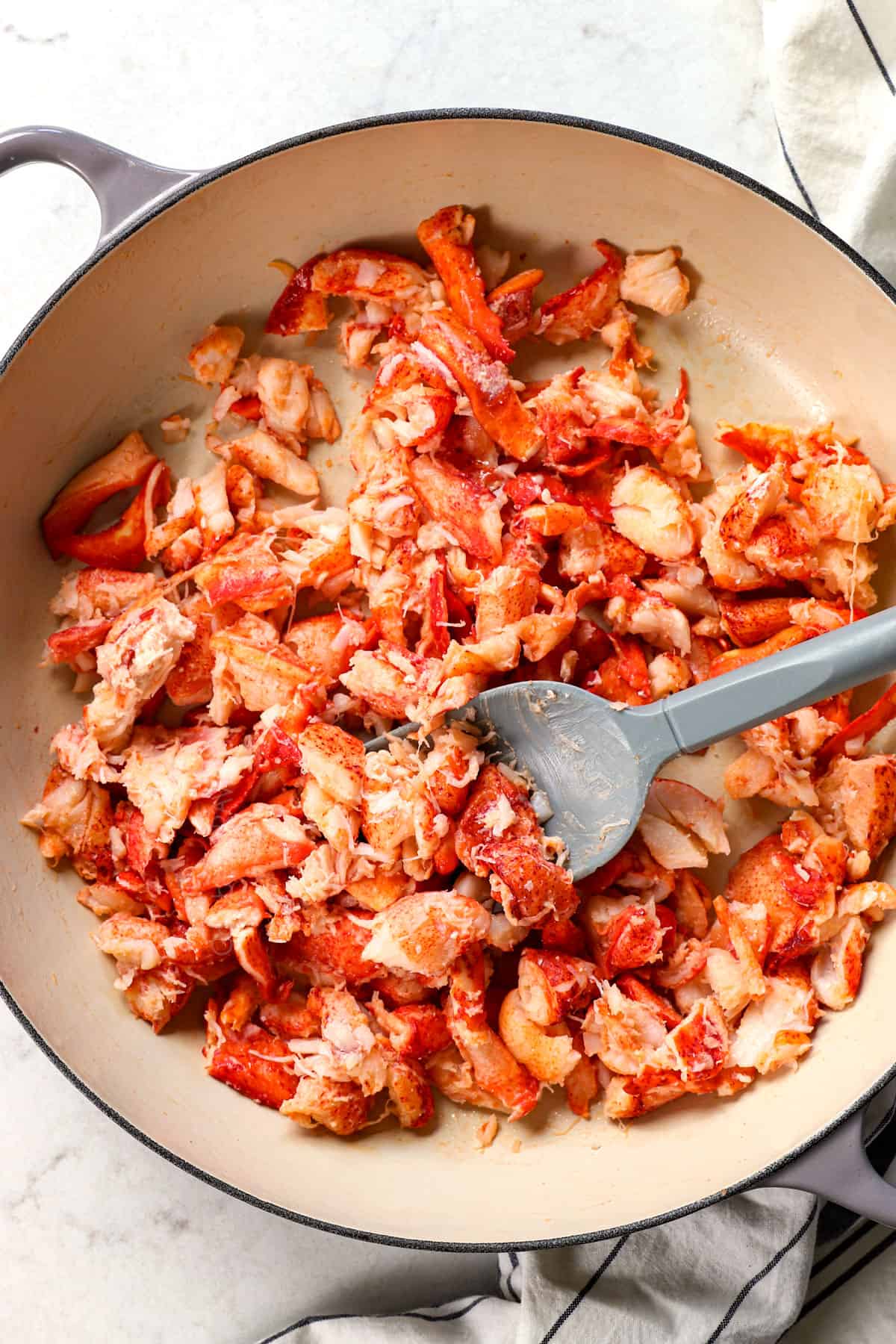 showing how to make a lobster roll by warming lobster in butter