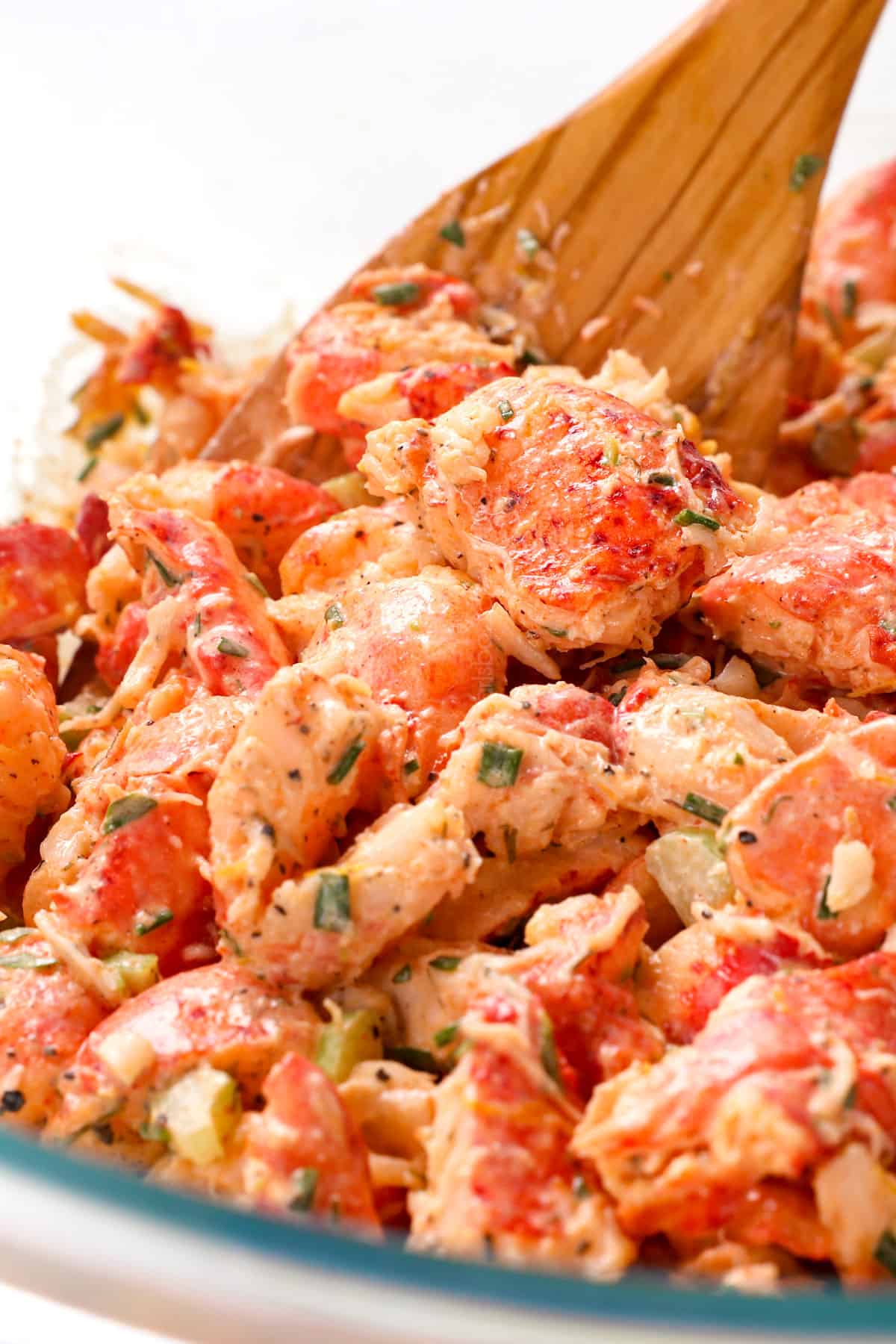 showing how to make a Maine lobster roll by tossing lobster in mayonnaise mixture