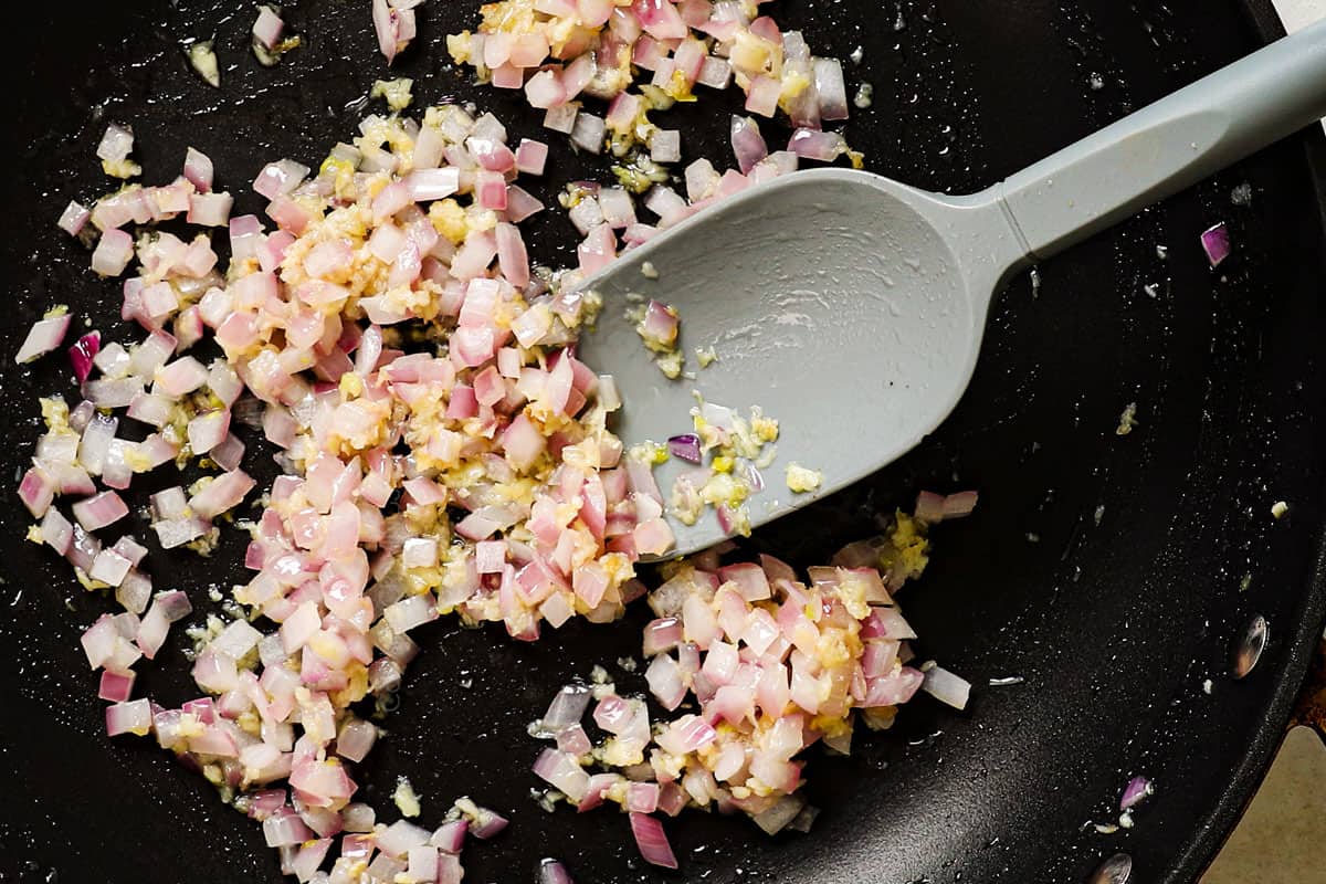 showing how to make chicken pasta salad by sautรฉing onions and garlic in a pan