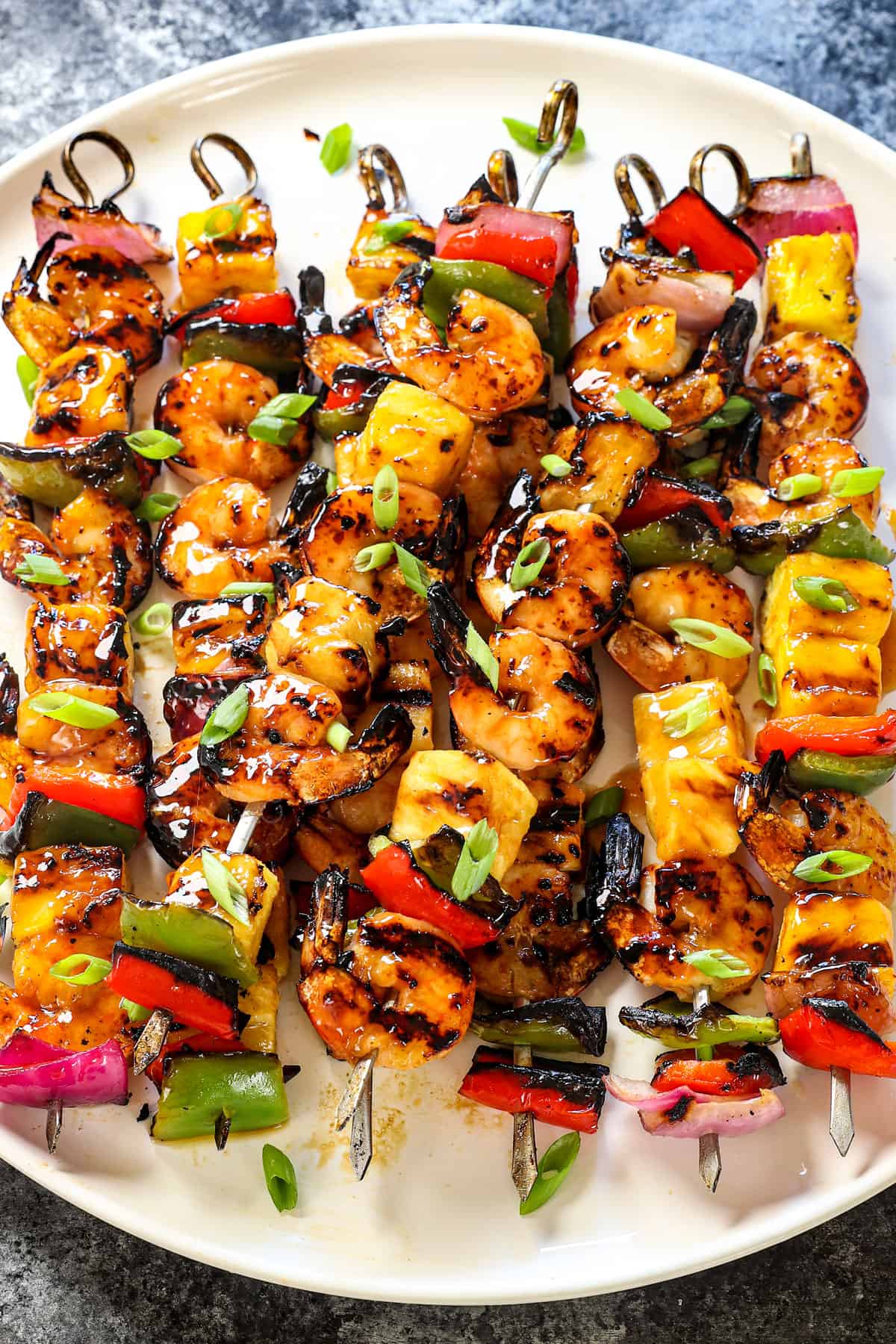 showing how to grill shrimp kabobs by garnishing with green onions on a plate