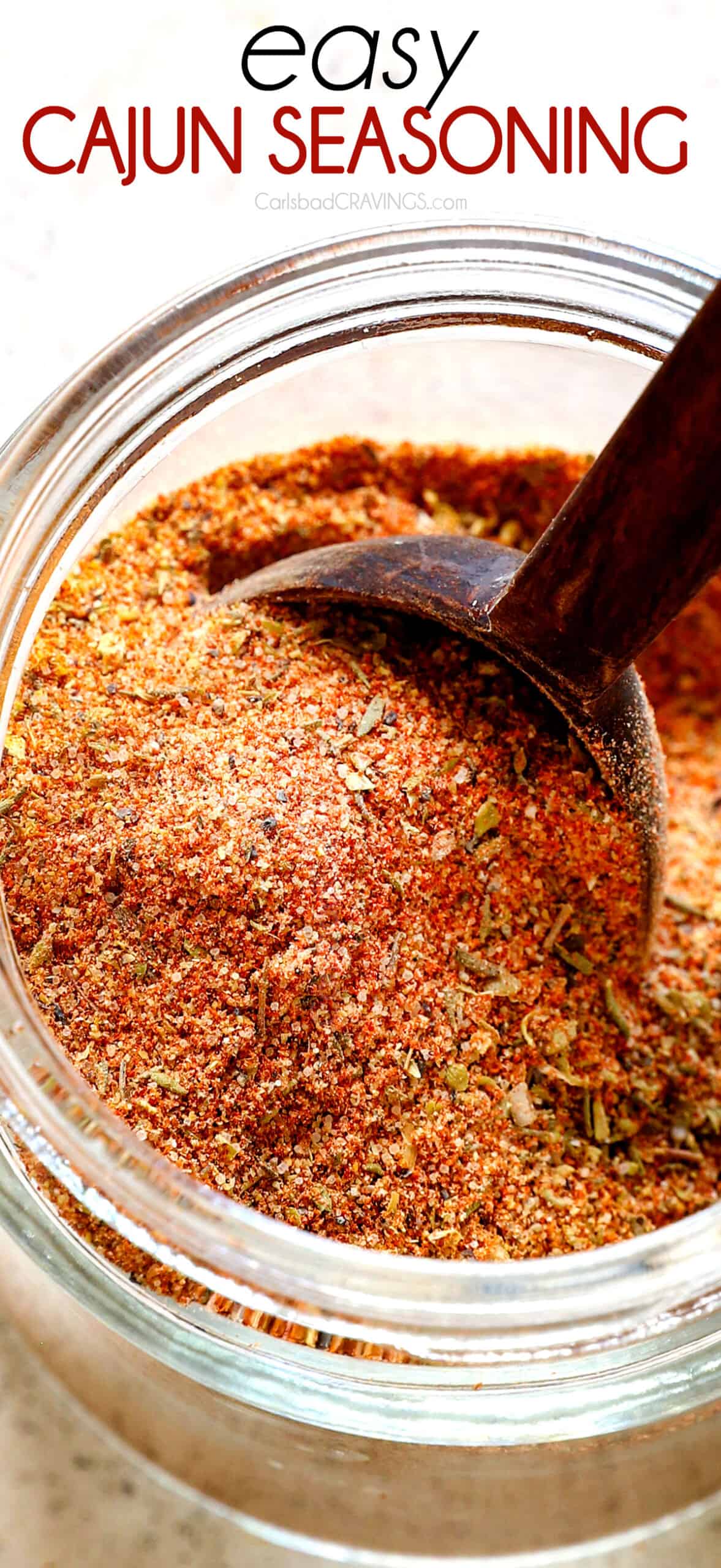 adding homemade Cajun seasoning to a glass jar