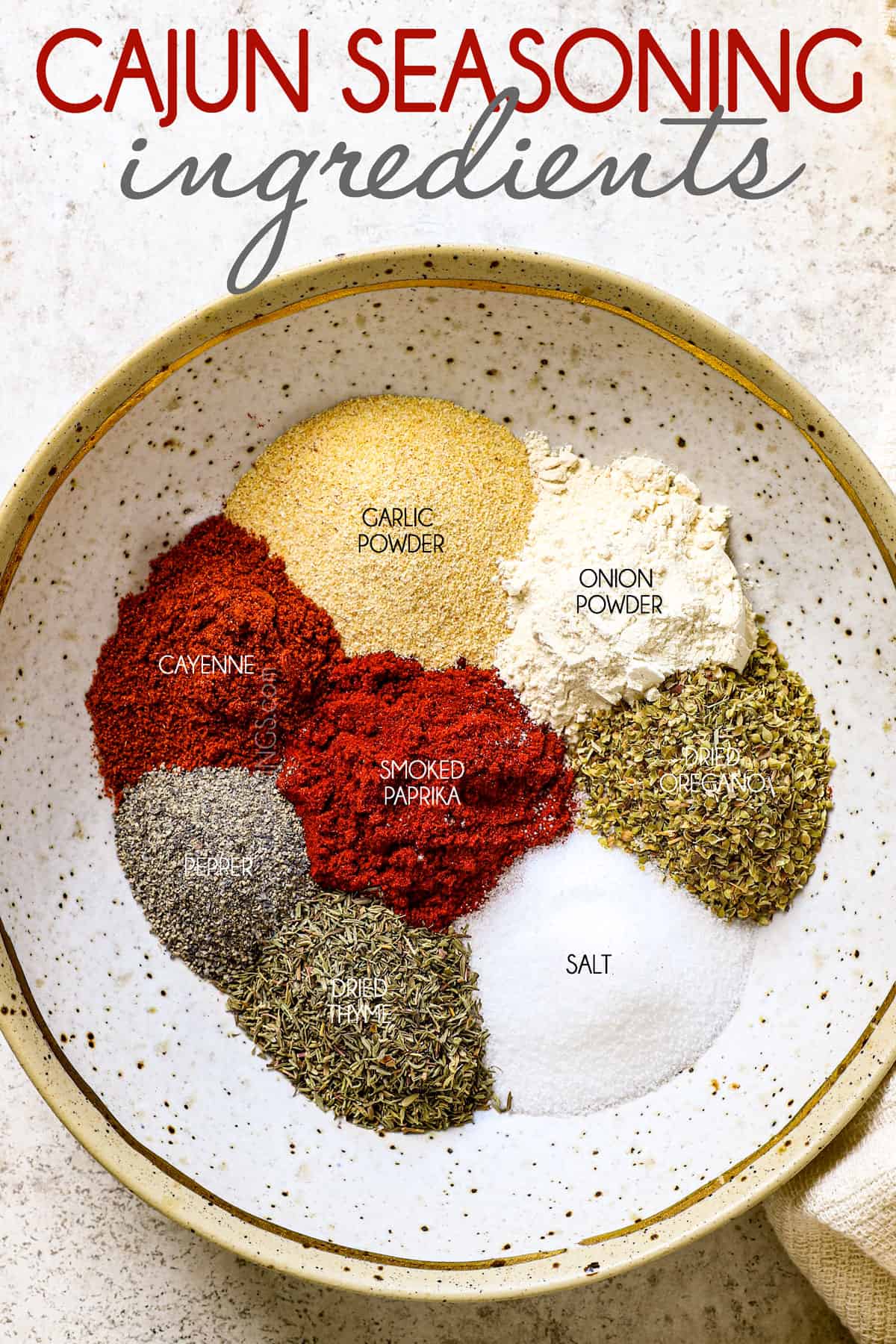 top view of Cajun seasoning recipe ingredients in a bowl: salt, garlic powder, onion powder, smoked paprika, pepper, cayenne pepper, oregano and thyme