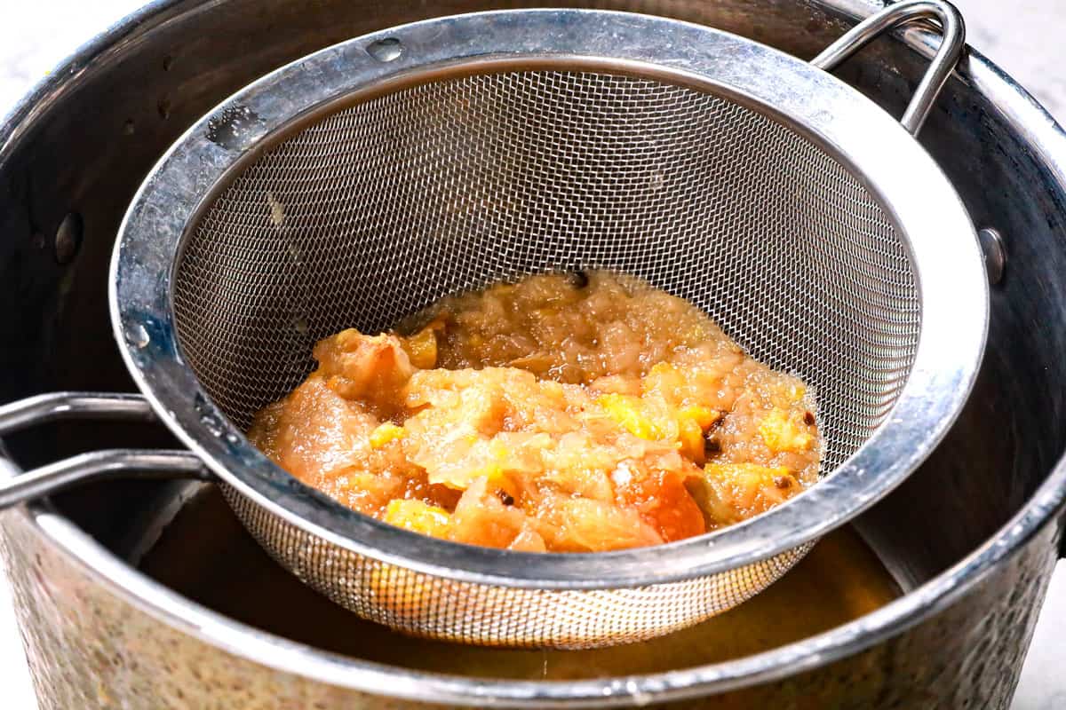 showing how to make apple cider recipe by straining mashed apples through a fine mesh siever