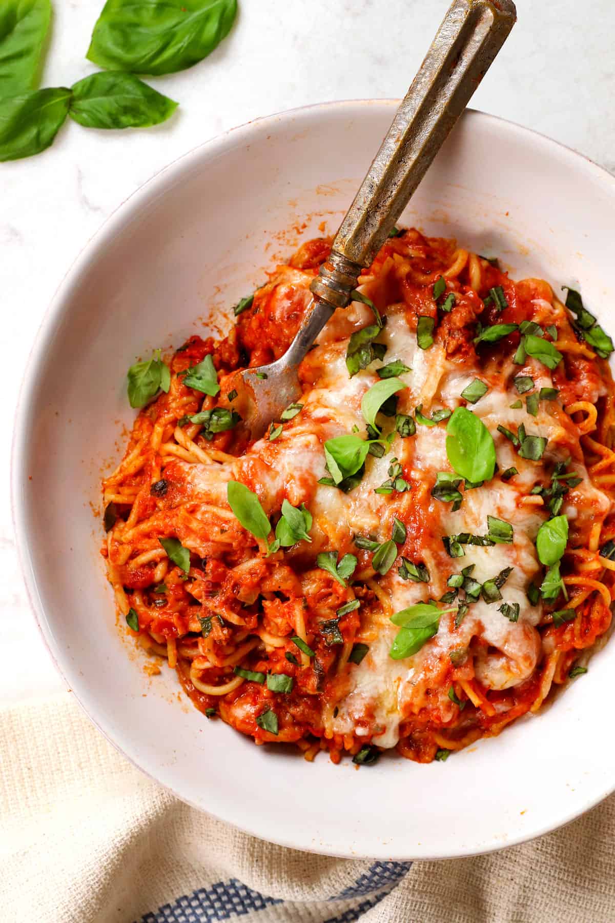 top view of serving baked spaghetti recipe on a plate garnished by basil