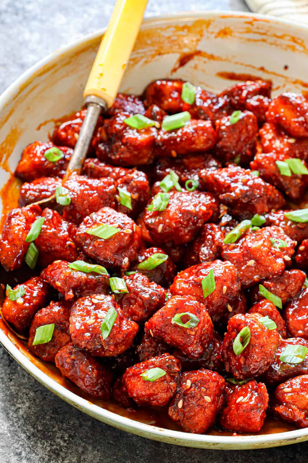 Korean fried chicken recipe (yangnyeom) in a skillet garnished with green onions and sesame seeds