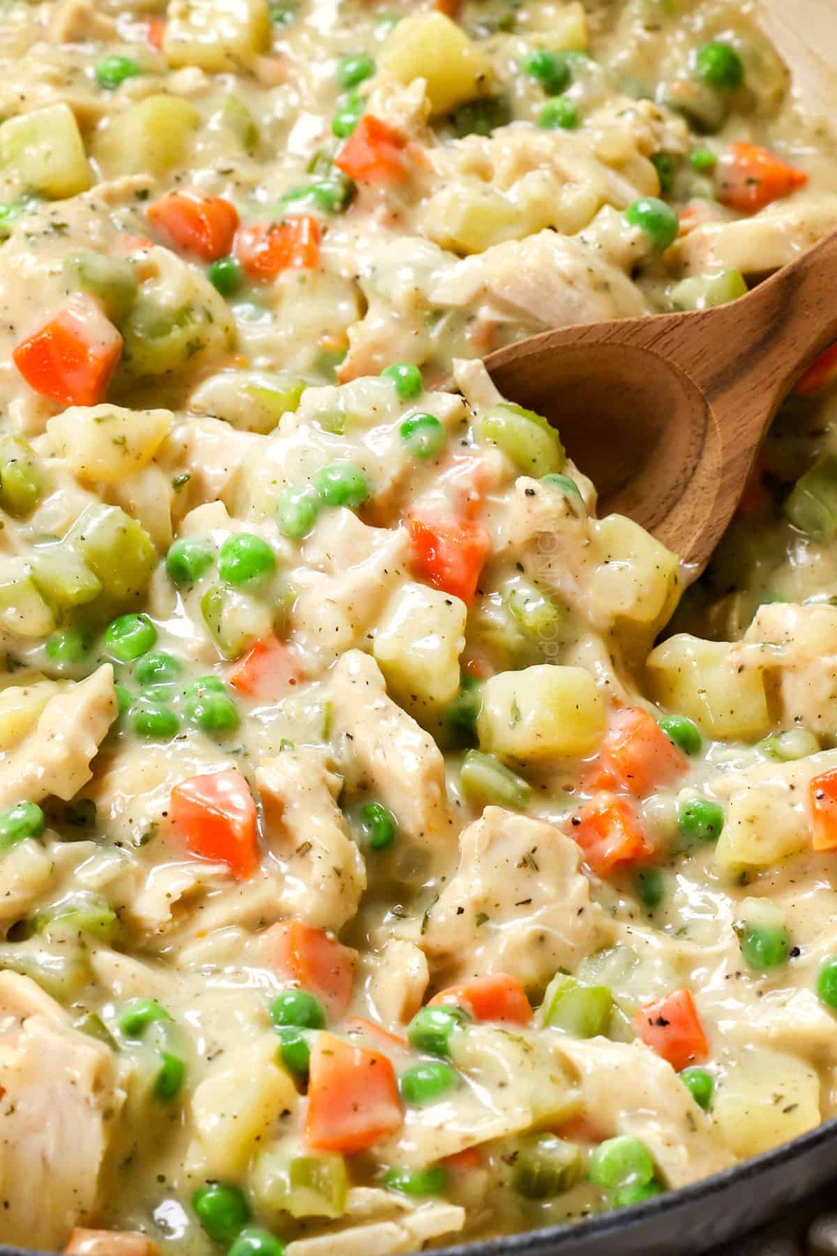 showing how to make turkey pot pie by stirring in turkey and peas into the sauce