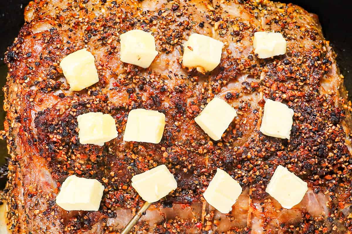 showing how to cook prime rib by adding cubed butter to the prime rib, then roasting