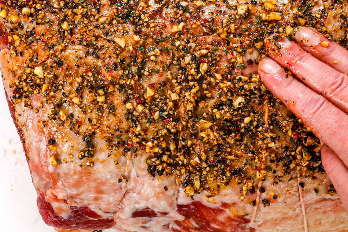 showing how to cook prime rib by rubbing peppercorn rub all over the prime rib