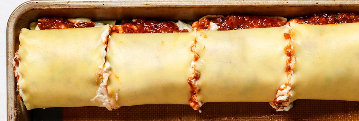 showing how to make lasagna lasagna roll ups by spreading lasagna noodles with cheese mixture, followed by rolling lasagna noodles up with filling