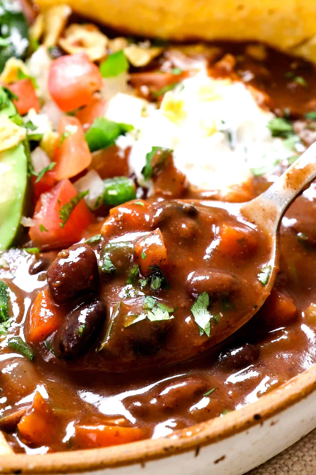 up close of a spoonful of black bean soup recipe showing how creamy it is with black beans, carrots, celery and bell peppers