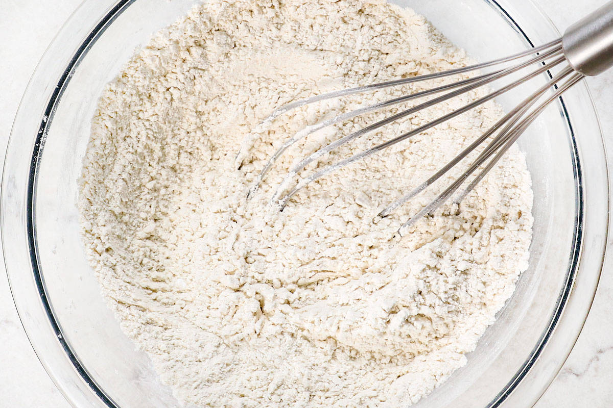 showing how to make pizookie by whisking flour, baking powder, cornstarch and sugar together in a bowl