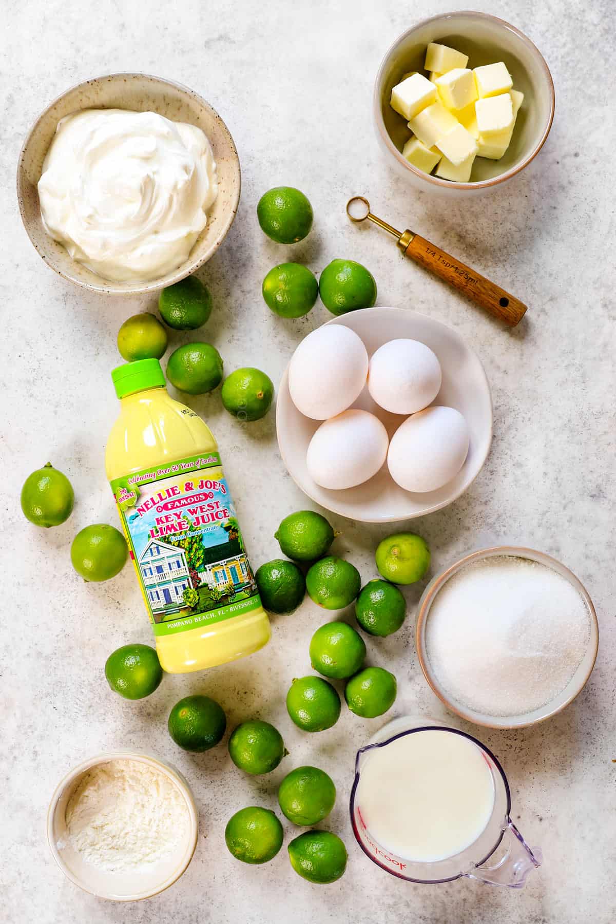 showing ingredients to make key lime pie recipe: key limes, egg yolks, sugar, heavy cream and butter