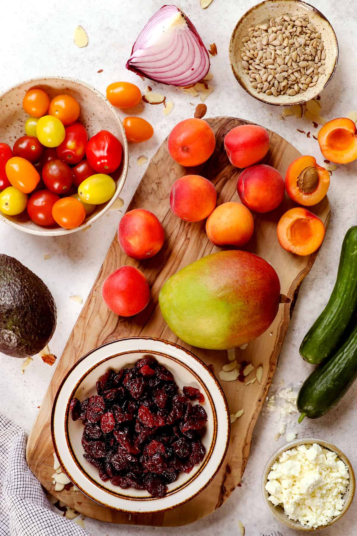 top view of summer salad recipe ingredients: cherries, mangos, peaches, tomatoes, cucumbers, avocado and red onions