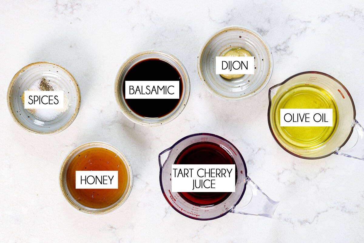 top view of summer salad dressing ingredients: olive oil, cherry juice, balsamic, honey, Dijon and spices