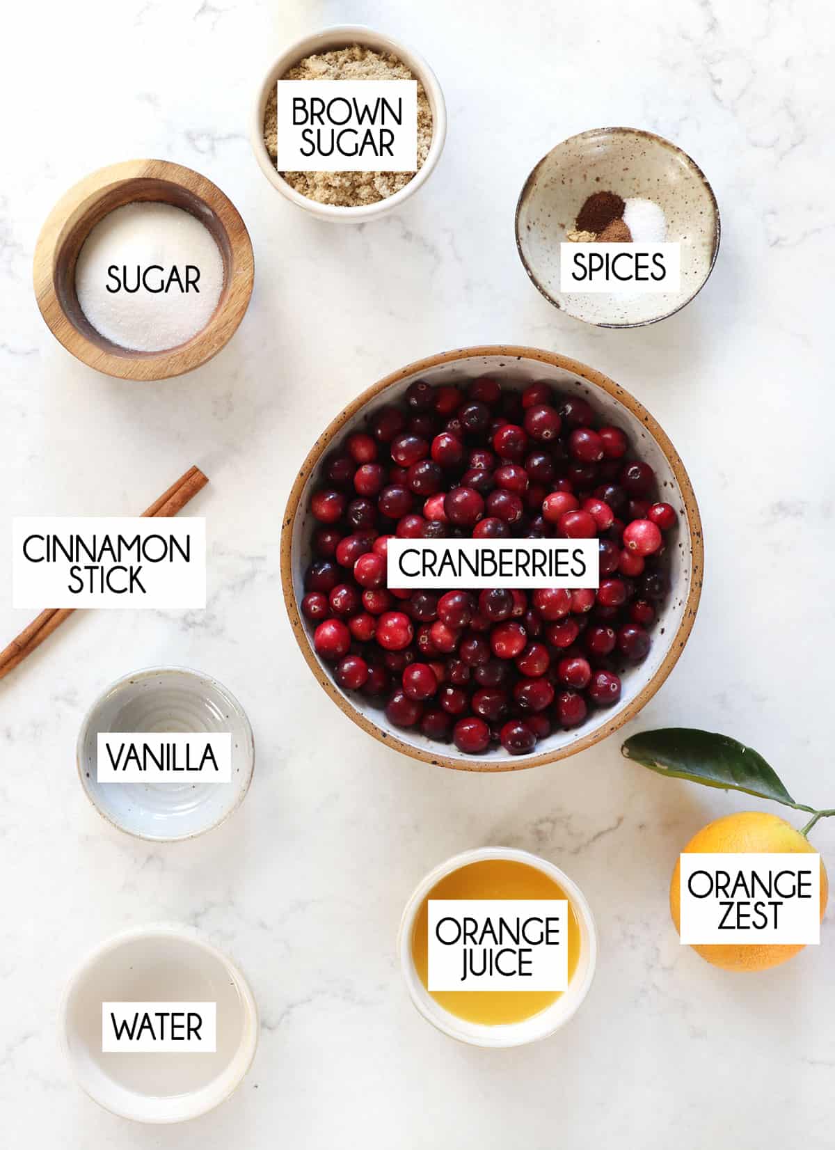 top view of cranberry sauce ingredients: fresh cranberries, orange juice, sugar, brown sugar, vanilla, cinnamon