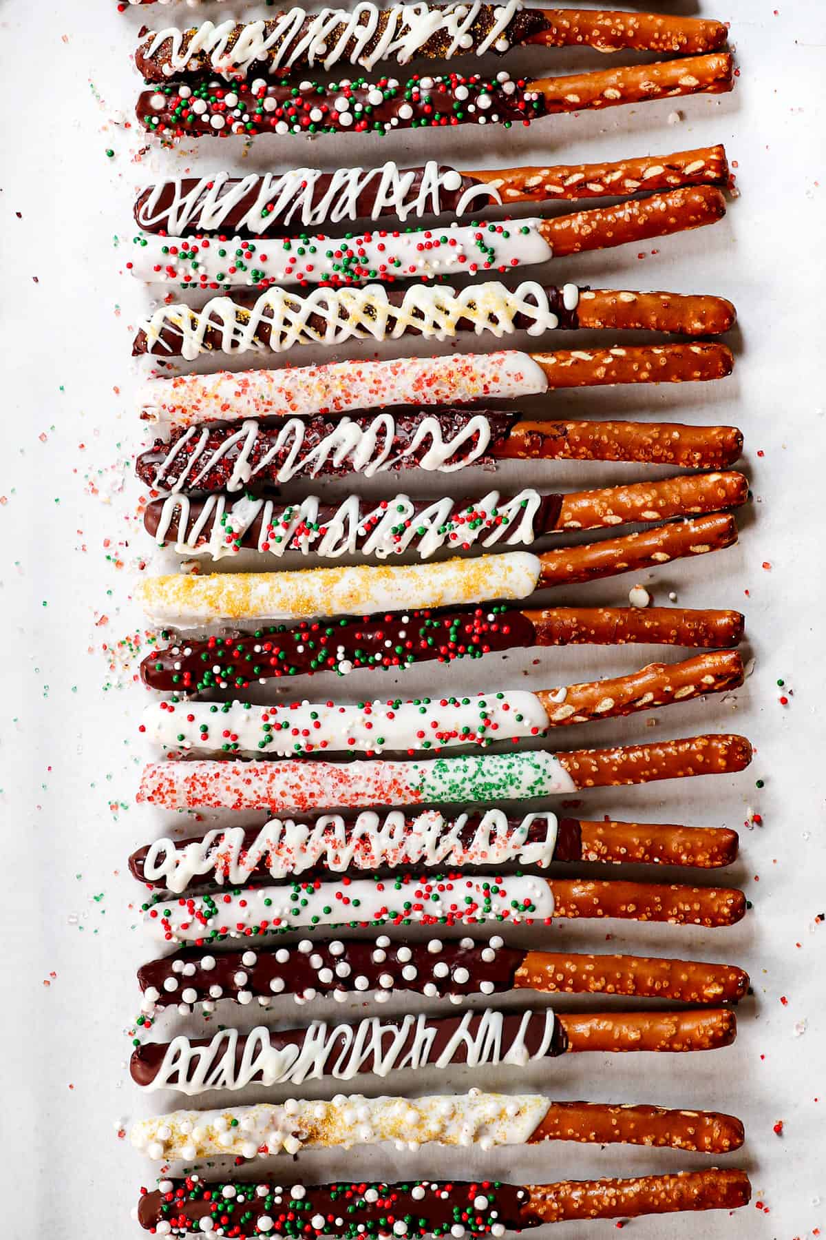 showing how to make chocolate covered pretzels by topping with sprinkles and letting them set on parchment paper
