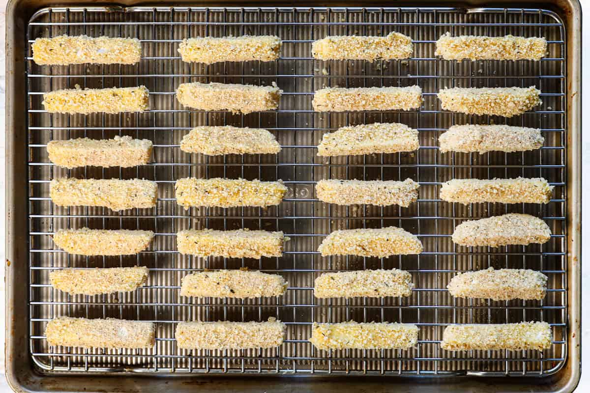 showing how to make mozzarella sticks by laying the breaded sticks onto a baking rack