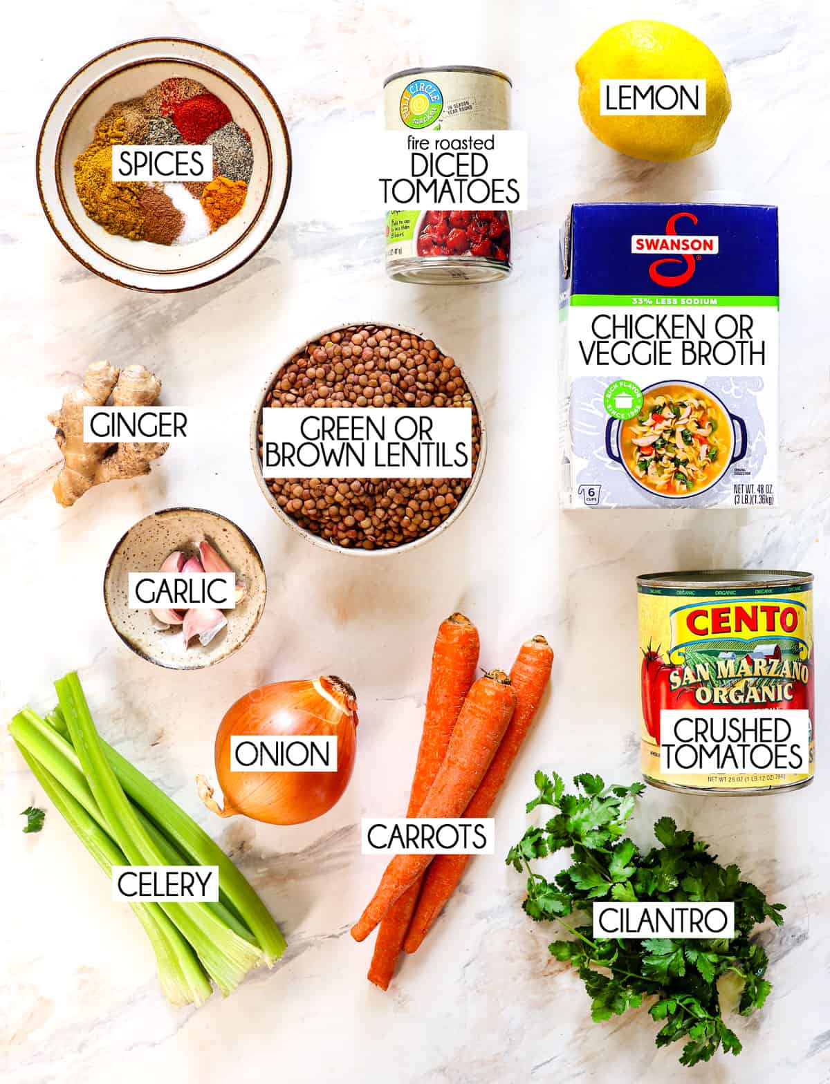 top view of lentil soup ingredients: green or brown lentils, vegetable broth, crushed tomatoes, diced tomatoes, garlic, onion, ginger, carrots, celery, cilantro, curry powder, spices and lemon