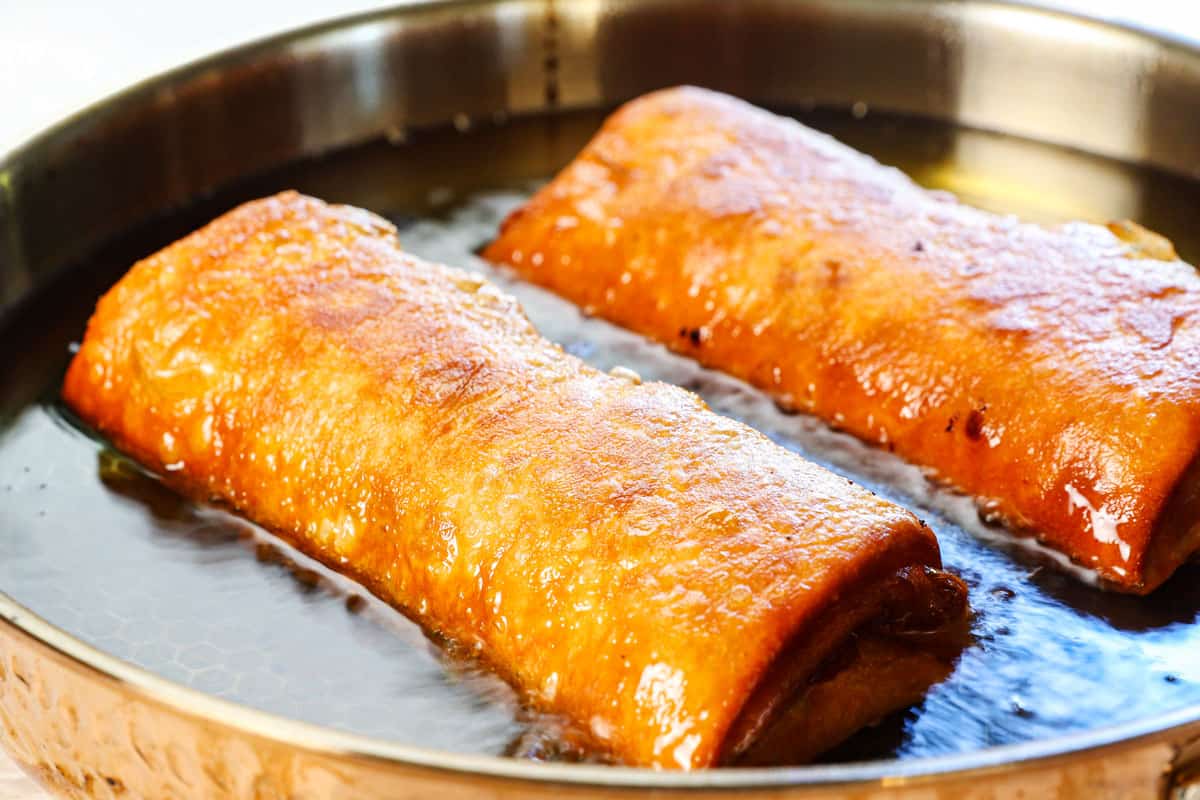 showing how to make chimichangas by deep frying two at a time