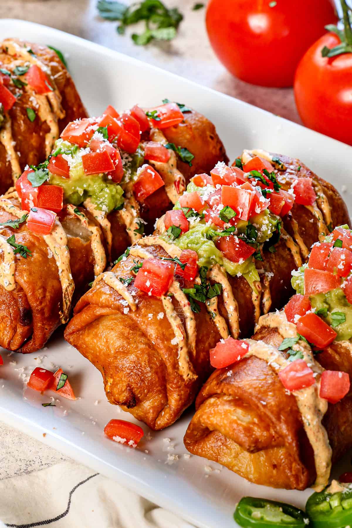 chimichangas lined on a plate garnished with crema