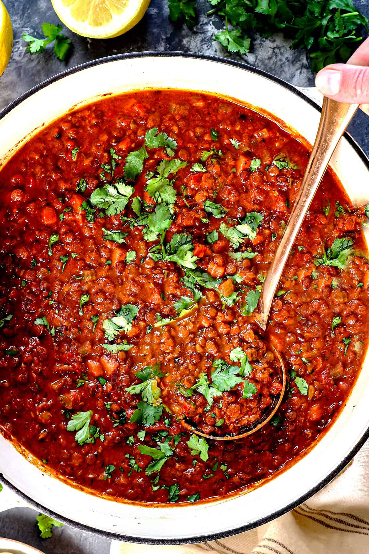 showing how to make lentil soup by adding the cilantro and lemon juice to the pot