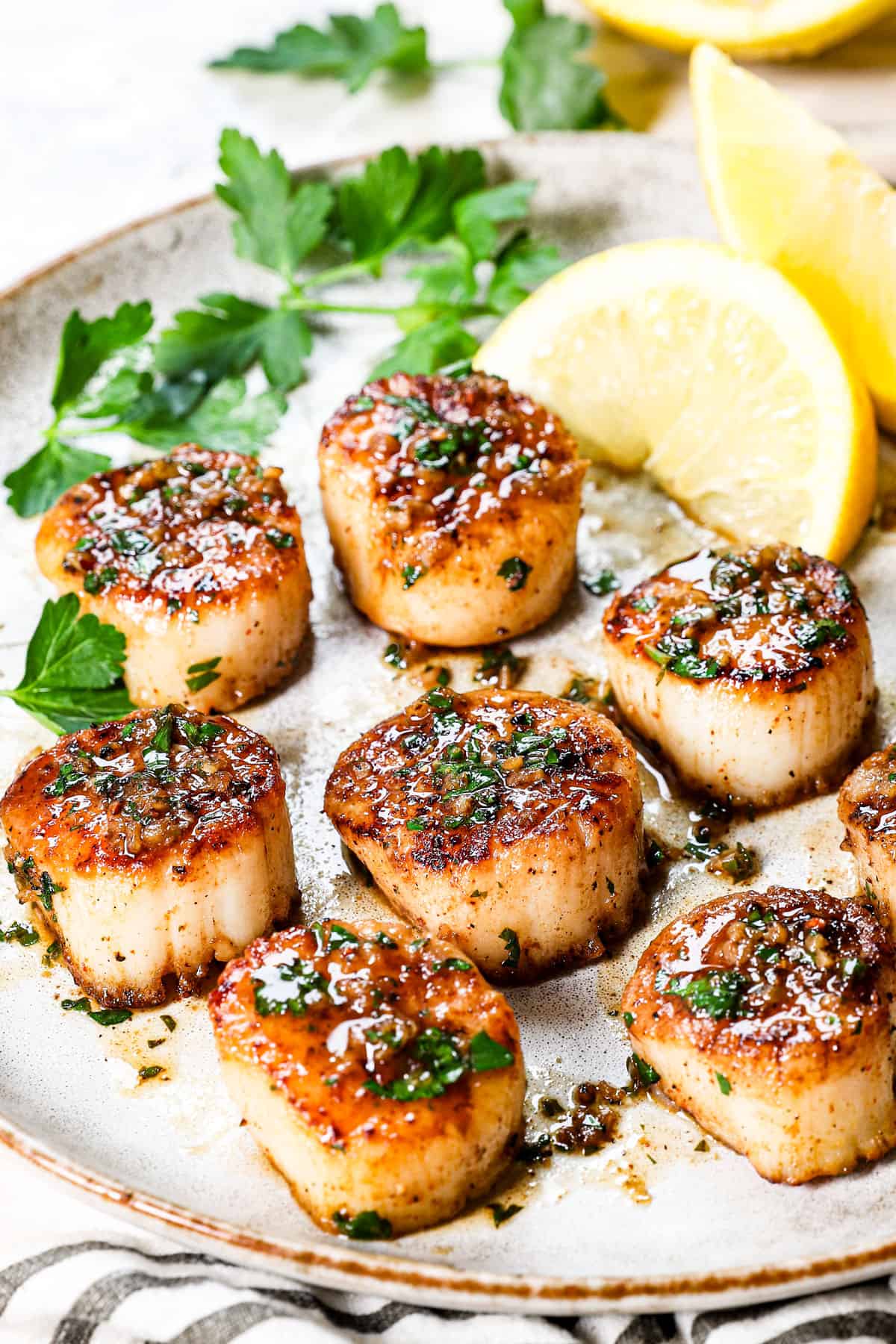 seared scallops recipe being served on a plate with lemon butter sauce drizzled over the top