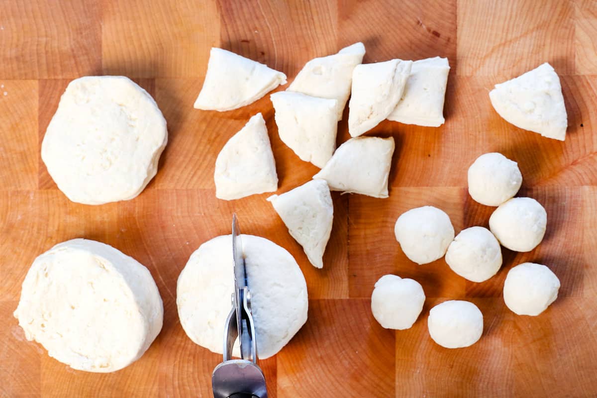showing how to make monkey bread by cutting the biscuits into 4 pieces each, then rolling into balls