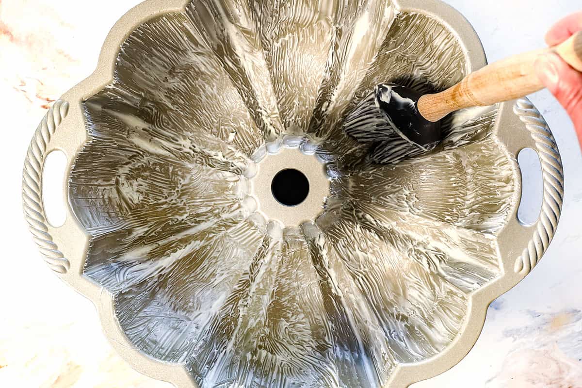 showing how to make monkey bread by greasing the pan with butter