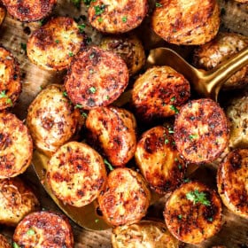 top view of scooping up roast potatoes on a baking sheet showing their crispiness