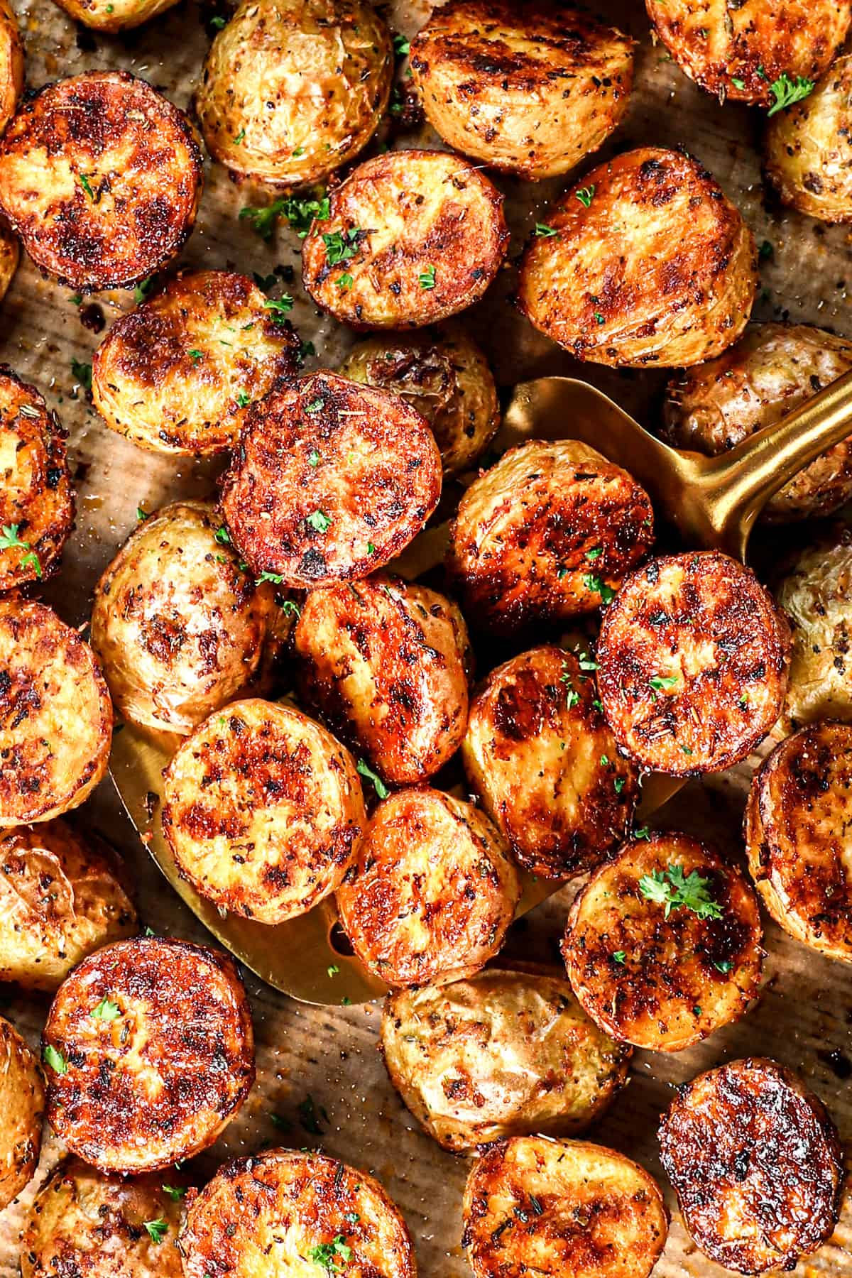 top view of scooping up roast potatoes on a baking sheet showing their crispiness