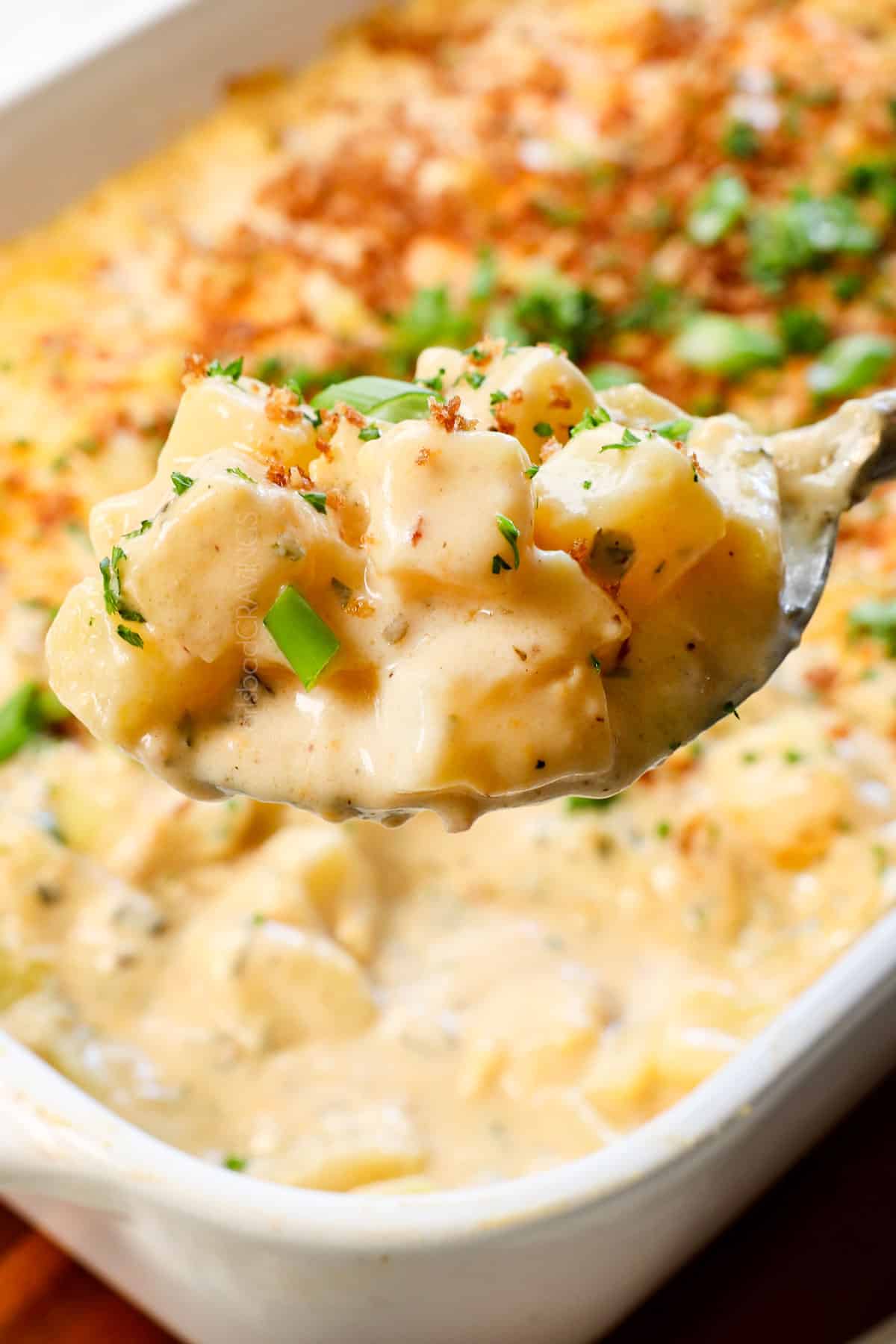 picking up a serving spoonful of cheesy potatoes recipe