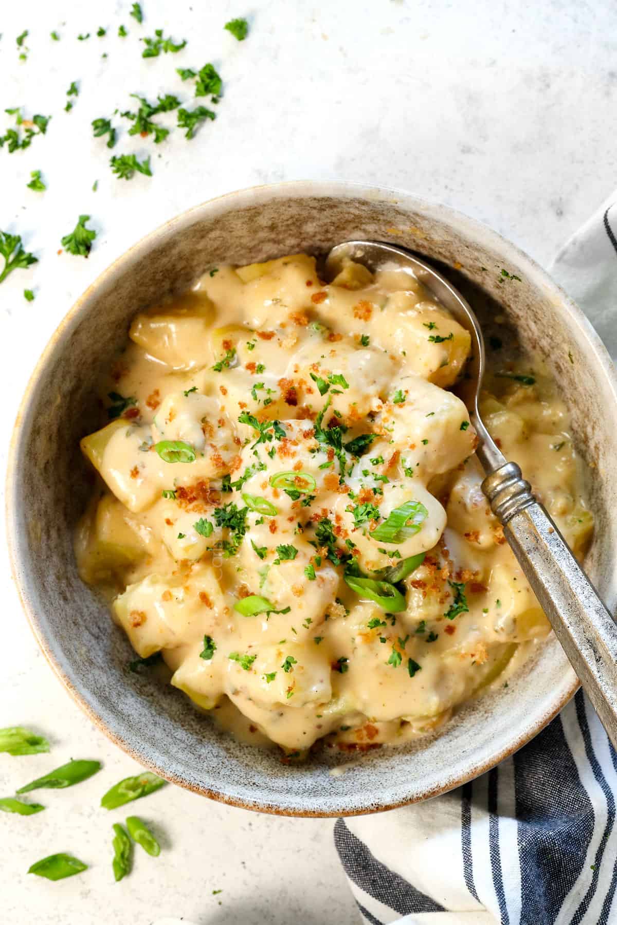top view of showing how to serve cheesy potatoes recipe in a bowl garnished with green onions and parsley