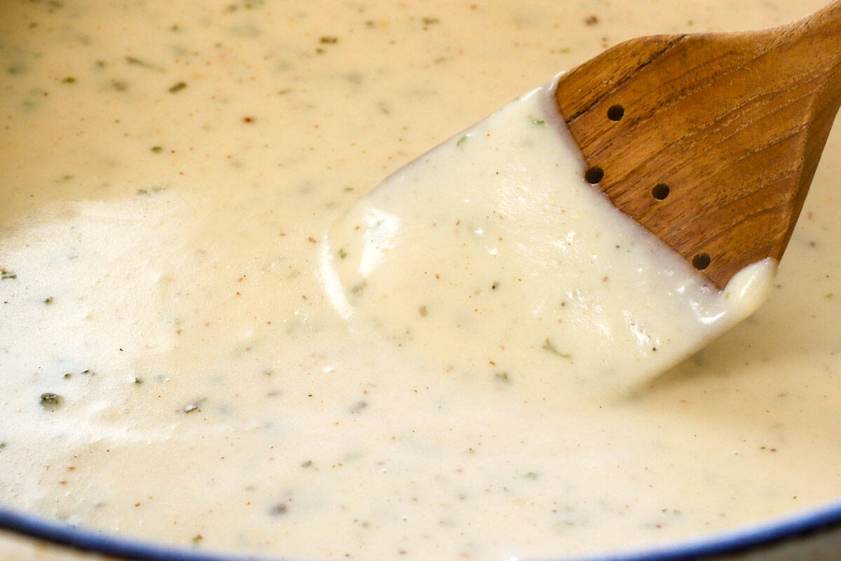 showing how to make cheesy potatoes by simmering the sauce until thickened