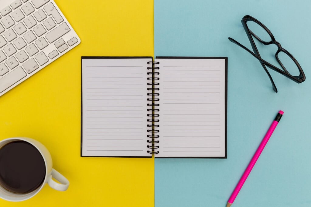 picture of notebook on a desk with glasses, coffee, pencil, and keyboard for article - best ways to make $30,000 a month