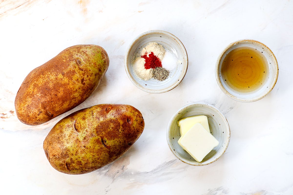 top view of hash brown ingredients: russet potatoes, butter, bacon grease, salt and pepper