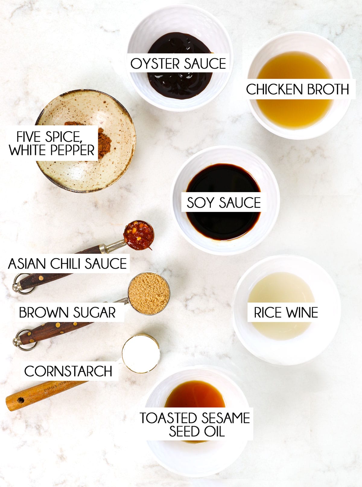 top view of low mein sauce ingredients: light soy sauce, dark soy sauce, oyster sauce, rice wine, brown sugar, cornstarch, Asian chili sauce,